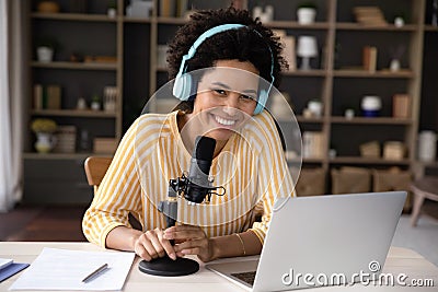 Happy young Black woman in headphones and professional microphone recording Stock Photo