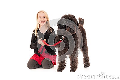 Happy young blonde girl holding black labradoodle on a red leash Stock Photo