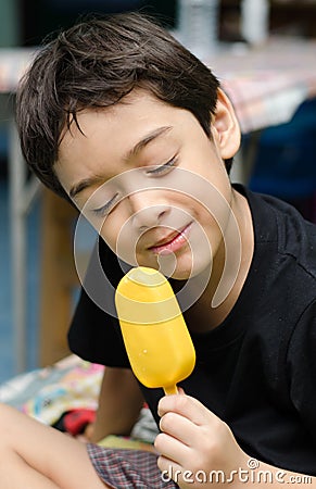 Happy young boy eating a tasty ice cream stick Stock Photo