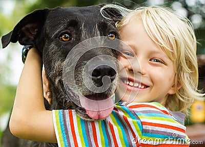 Happy young boy lovingly hugging his pet dog Stock Photo