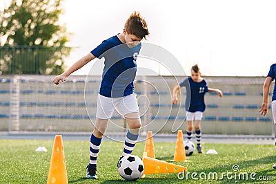 Happy young boy running and kicking the soccer ball in training Stock Photo