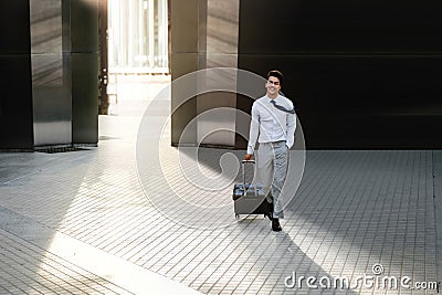 Happy Young Businessman Walking with Suitcase in the City. Modern Male in Business Trip. Front View Stock Photo