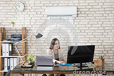 Businesswoman Working In Office With Air Conditioning Stock Photo