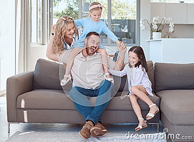 Happy young caucasian family sitting on a sofa in the living room at home and playing. Adorable little girls and their Stock Photo