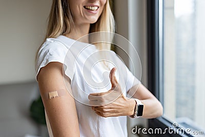 Happy young caucasian woman with blonde hair in white t-shirt showing patch on arm, feeling good after anti coronavirus Stock Photo