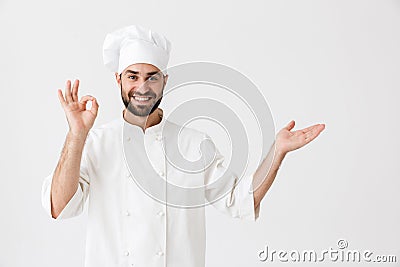 Happy young chef posing isolated over white wall background in uniform make okay gesture showing copyspace Stock Photo