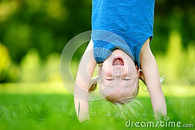 Happy young child playing head over heels on green grass Stock Photo