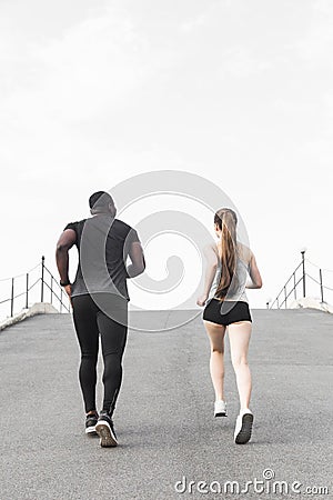 Happy young couple afro-american man and european woman running together. A loving couple is run, engaged in sports Stock Photo
