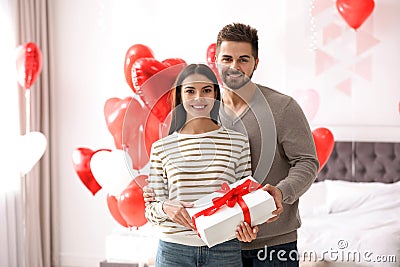 Happy young couple in bedroom decorated with heart balloons. Valentine`s day celebration Stock Photo