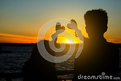 Happy young couple with decorative hearts on river bank at sunset Stock Photo