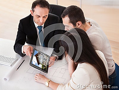 Happy Young Couple Discussing With Consultant Stock Photo
