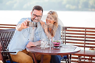 Happy young couple drinking coffee in a cafe, taking a selfie Stock Photo
