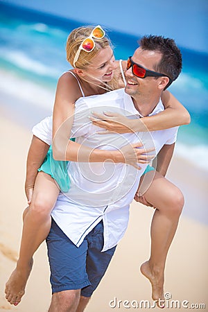 Happy young couple enjoying a solitary beach backriding Stock Photo