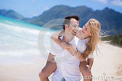 Happy young couple enjoying a solitary beach backriding Stock Photo