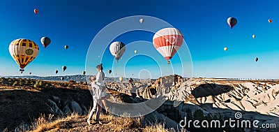 A happy young couple enjoys balloons during sunrise in Cappadocia, Turkey, panorama. Travel to the tourist places of Turkey Editorial Stock Photo