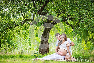 Happy young couple expecting baby, pregnant woman with husband touching belly Stock Photo