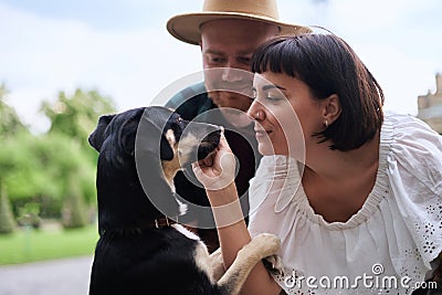 Happy young couple feeding their rescued dog in old city background in summer Stock Photo