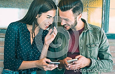 Happy young couple having fun with mobile smart phone at urban place - Friendship concept with best friends connecting and sharing Stock Photo