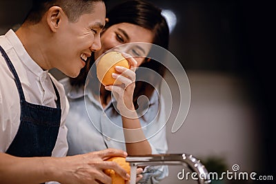 Happy Young Couple in the Kitchen. Cleaning some Oranges to Preparing Delicious Menu. Cooking Together Stock Photo