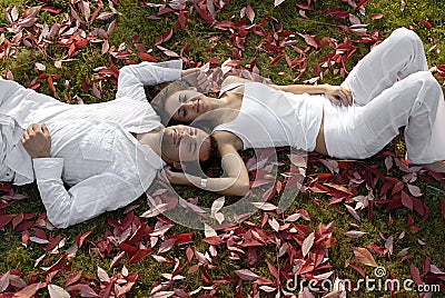 Happy young couple lying in autumn leaves Stock Photo