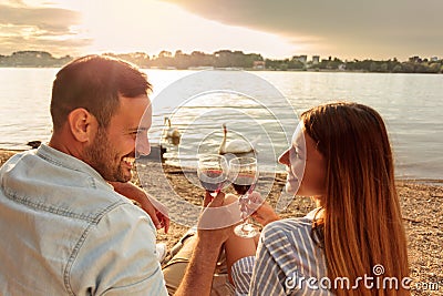 Happy young couple making a toast with red wine. Enjoying picnic at the beach Stock Photo