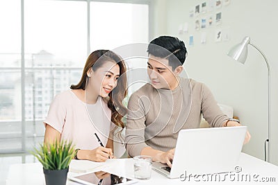 Happy young couple reading and analyzing bills sitting at table. Stock Photo