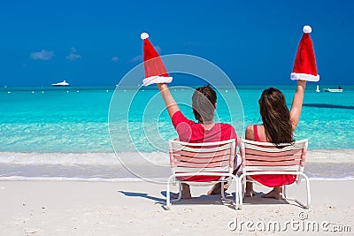 Happy young couple in red Santa Hats sitting on Stock Photo