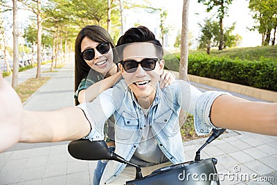 Happy young couple riding scooter and making selfie photo Stock Photo