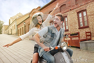 Happy young couple riding scooter in town. Handsome guy and young woman travel. Adventure and vacations concept. Stock Photo