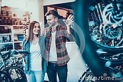 Happy Young Couple Talk about Wheel in Bike Shop Stock Photo