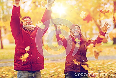 Happy young couple throwing autumn leaves in park Stock Photo