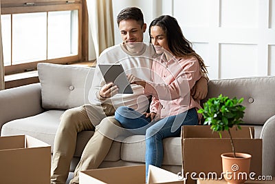 Happy young couple using computer tablet, choosing moving service Stock Photo