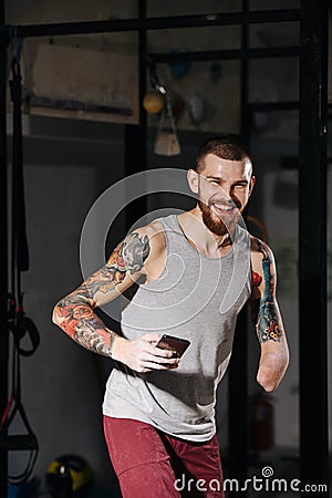 Happy young disabled armless man in a training room with a phone in hand Stock Photo