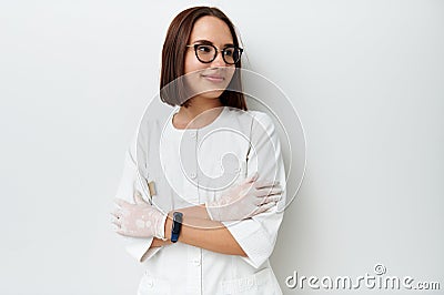 Happy young doctor intern looking away while posing against white background with crossed arms Stock Photo