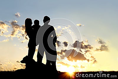 Happy Young Family and Dog Silhouette at Sunset Stock Photo