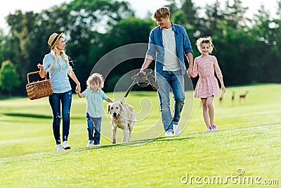 happy young family with pet walking on green meadow Stock Photo