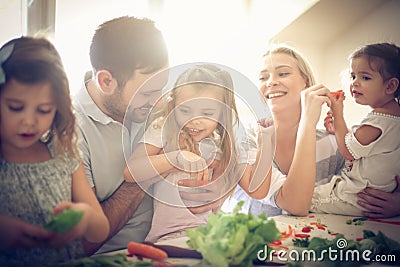 Happy young family preparing salad together. Stock Photo