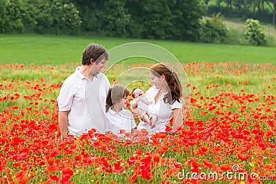 Happy young family standing in poppy flower field Stock Photo