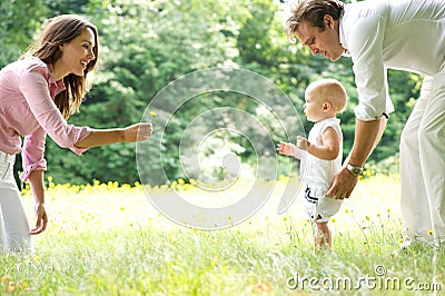 Happy young family teaching baby to walk Stock Photo