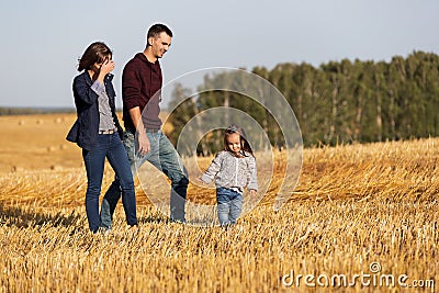 Happy young family with two year old girl walking in harvested field Stock Photo