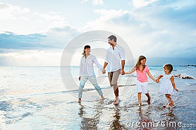 Happy young family walking on the beach Stock Photo