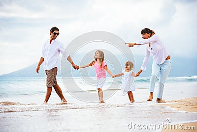 Happy young family walking on the beach Stock Photo