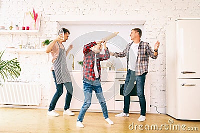 Happy young gay homosexual family with son boy 8 years old have fun in the kitchen, dance with cooking utensils Stock Photo