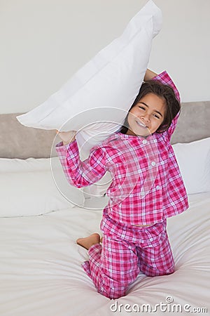 Happy young girl holding up a pillow in bed Stock Photo