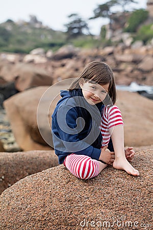 Happy young girl smiling, relaxing on a giant granite stone Stock Photo