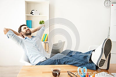 Happy young guy is relaxing at work Stock Photo