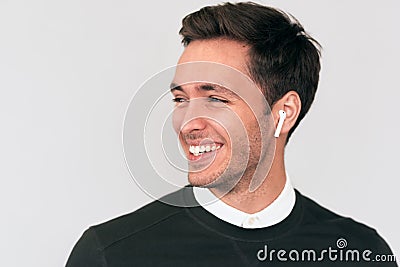 Happy young handsome man speaking with a friend telling good news using earbuds. Positive Caucasian businessman using wireless Stock Photo