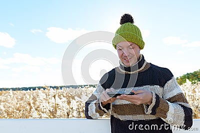 Happy young handsome man using phone against scenic view of autumn bulrush field Stock Photo