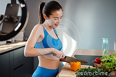 Happy young healthy woman influencer preparing fresh salad Stock Photo