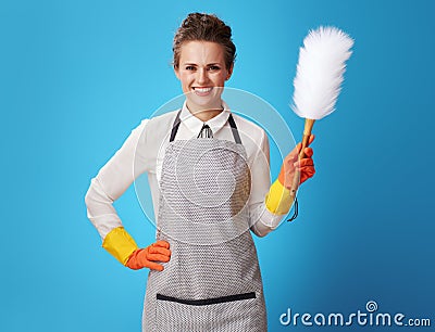 Happy young housemaid with dust cleaning brush on blue Stock Photo